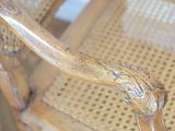 a close up of a wooden chair with a wicker seat