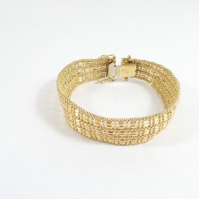 gros plan d'un bracelet en or sur fond blanc