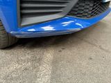 the front bumper of a blue car with a black grille