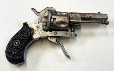 un vieux revolver argenté avec une crosse noire sur un fond blanc