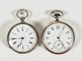 deux montres de poche en argent posées côte à côte sur une surface blanche
