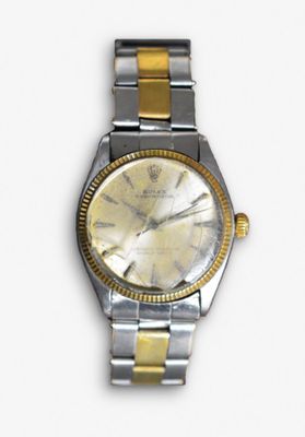 une montre argentée et dorée posée sur une surface blanche