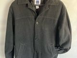 grey wool jacket hanging on a hanger on a white sheet