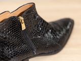 black snake skin ankle boots with gold zippers on a wooden floor