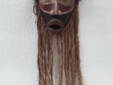 an image of a wooden mask hanging on a white wall