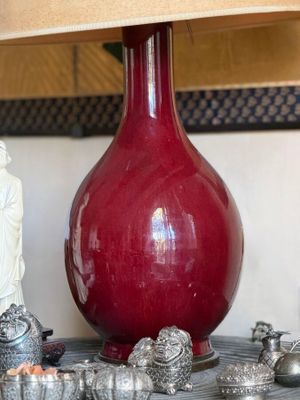 a red vase with a buddha figurine next to it