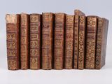 several old books are lined up in a row on a white surface