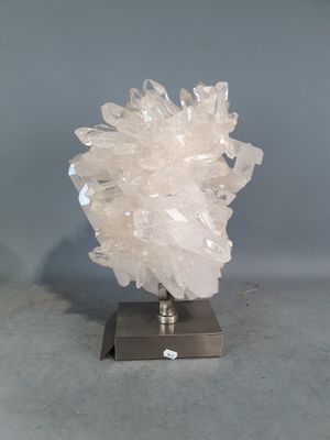 grappe de cristaux posée sur un socle métallique, sur fond gris avec un fond blanc