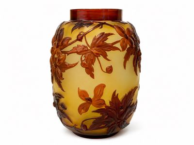 un vase jaune orné de feuilles marron sur un fond blanc