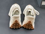 pair of white shoes with brown soles sitting on a table