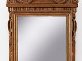 un miroir ancien en bois orné d'une sculpture représentant un oiseau sur le dessus