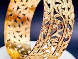 un gros plan d'un bracelet en or posé sur une assiette blanche