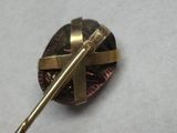 une broche en or ornée d'une croix, posée sur un fond blanc