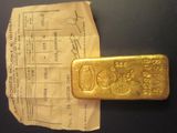 un lingot d'or posé sur un bout de papier à côté d'un ticket de caisse