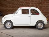 a small white car parked in front of a brick wall