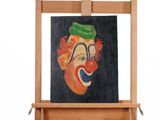 un tableau représentant un clown coiffé d'un chapeau vert, posé sur un chevalet