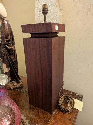 une statue représentant un homme assis sur une table, à côté d'un vase