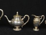 four pieces of silver tea and coffee set on a black background