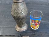 un vase en argent et un verre posés sur une table