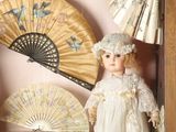 a picture of a doll in a shadow box with a fan
