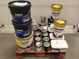 Plusieurs pots de peinture sont empilés sur une palette dans un entrepôt
