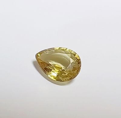 gros plan d'une pierre de saphir jaune sur une surface blanche