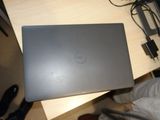 someone is holding a dell laptop on a desk with a charger on it