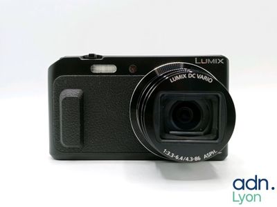 a black camera sitting on a table with a white background