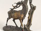 bronze sculpture of a stag on a rock with antelope in its mouth
