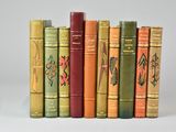 several old books are lined up in a row on a white surface