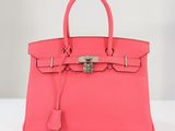 un sac à main en cuir rose muni d'un fermoir métallique sur la poignée
