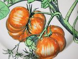 three orange tomatoes on the vine on the plate