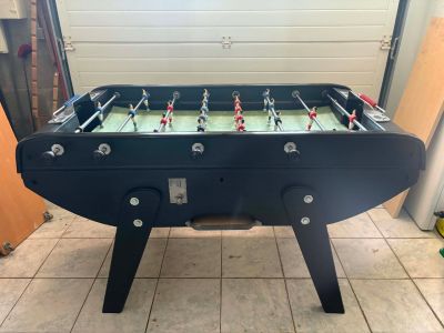 une table de baby-foot dans un garage, avec la porte du garage en arrière-plan