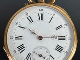 a gold pocket watch with roman numerals on the face