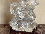 une statue en verre représentant une personne assise sur une table
