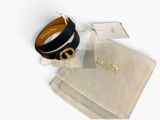 the bracelet is black and gold with a gold logo on it