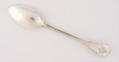 une cuillère en argent posée sur une surface blanche, avec une petite cuillère au milieu
