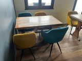 brightly colored chairs sit around a wooden table in a small room