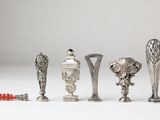 five silver vases and a red toothbrush on a white surface