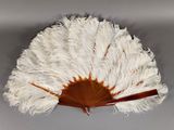 white and brown ostrich fan with wooden handle on grey background