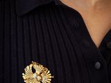 a close up of a woman wearing a black shirt and a gold brooch