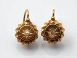 l'image d'une paire de boucles d'oreilles en or sur une surface blanche