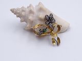 une broche en or ornée d'une fleur verte et blanche