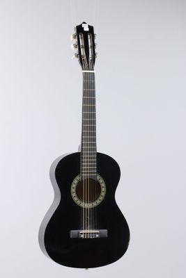 an image of a black acoustic guitar hanging on a white wall