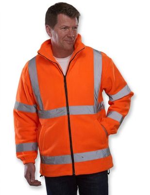 un homme vêtu d'une veste orange, debout, les mains dans les poches