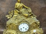une horloge en or avec une femme assise dessus
