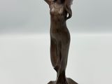 une statue en bronze représentant une femme, les mains posées sur la tête