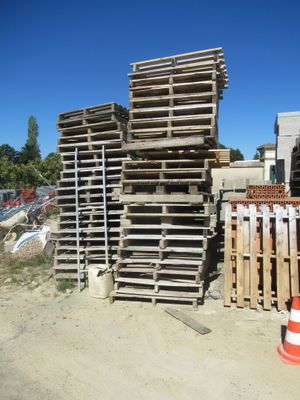 une pile de palettes posée à côté d'un cône de signalisation