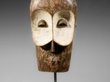 une image représentant un masque en bois posé sur un socle métallique
