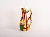 un vase jaune et rouge posé sur une surface blanche